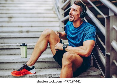 Handsome male jogger listening to music while taking break after morning training in urban setting - Powered by Shutterstock