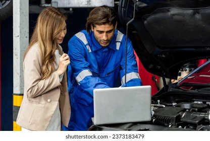 Handsome male mechanic wearing uniform, using laptop, checking or inspecting for fix, repair car or automobile components, talking with customer, working in car maintenance service center or shop - Powered by Shutterstock