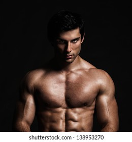 A handsome male model posing at a studio in front of a black background.