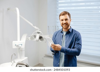 Handsome male patient looking at his beautiful smile standing at the dental office. - Powered by Shutterstock