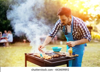 HAndsome male preparing barbecue outdoors for friends