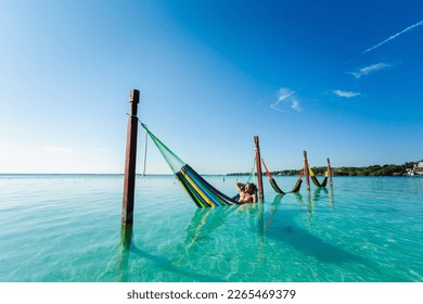 Handsome male tourist relaxing in a hammock in Laguna Bacalar in Mexico during kayak trip.