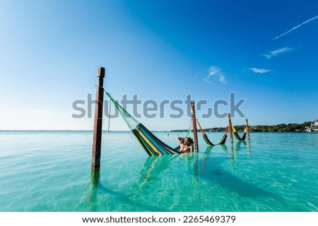Handsome male tourist relaxing in a hammock in Laguna Bacalar in Mexico during kayak trip.