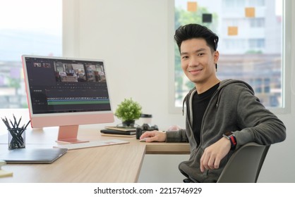 Handsome male video editor sitting front of professional computer in creative office studio and smiling to camera. - Shutterstock ID 2215746929