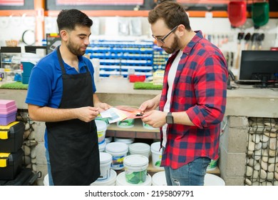 Handsome Male Worker At The Hardware Store Helping A Customer To Find The Perfect Color Paint Swatch To Paint His House 