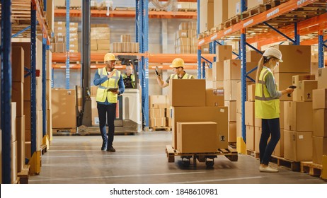 Handsome Male Worker Wearing Hard Hat Holding Digital Tablet Computer Walking Through Retail Warehouse Full Of Shelves With Goods, Greeting Workers. Working In Logistics And Distribution Center.