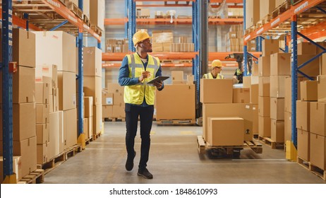 Handsome Male Worker Wearing Hard Hat Holding Digital Tablet Computer Walking Through Retail Warehouse full of Shelves with Goods. Working in Logistics and Distribution Center. - Powered by Shutterstock