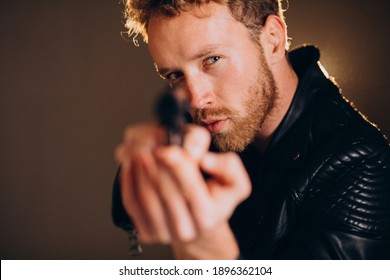 Handsome man actor posing in studio with weapon