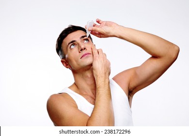 Handsome Man Applying Eye Drop Over Gray Background