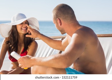 Handsome man applying sun cream on his girlfriends nose on the beach - Powered by Shutterstock