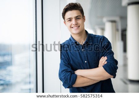 Handsome man with arms crossed looking at camera near of the window