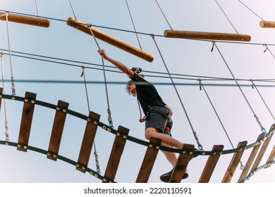 Handsome man balancing himself on the ladder in the adventure park - Powered by Shutterstock