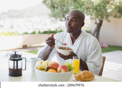 Handsome Man In Bathrobe Having Breakfast Outside On A Sunny Day