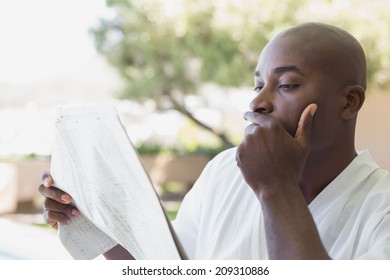 Handsome Man In Bathrobe Reading Newspaper Outside On A Sunny Day