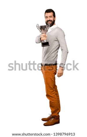 Handsome man with beard holding a trophy over isolated white background