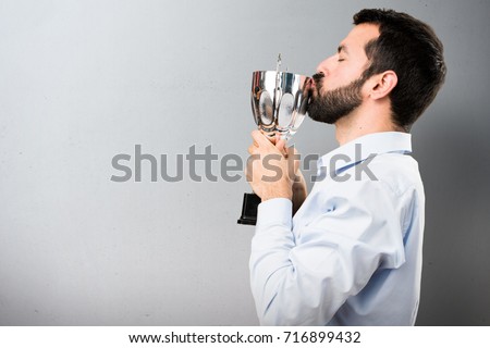 Handsome man with beard holding a trophy on textured background