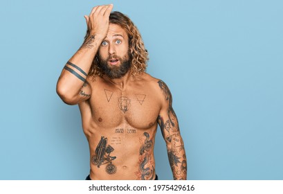 Handsome Man With Beard And Long Hair Standing Shirtless Showing Tattoos Surprised With Hand On Head For Mistake, Remember Error. Forgot, Bad Memory Concept. 