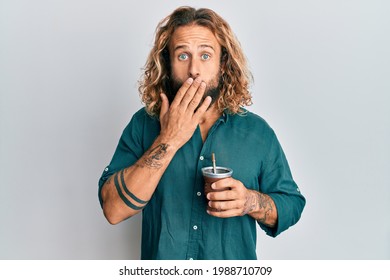 Handsome Man With Beard And Long Hair Drinking Mate Infusion Covering Mouth With Hand, Shocked And Afraid For Mistake. Surprised Expression 