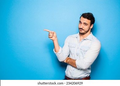 handsome man with beard pointing in one direction on a blue background