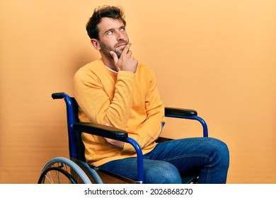 Handsome man with beard sitting on wheelchair with hand on chin thinking about question, pensive expression. smiling with thoughtful face. doubt concept.  - Powered by Shutterstock