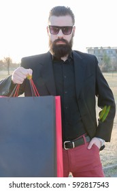 handsome man with a beard in a suit shows shopping bags with space for text, high key