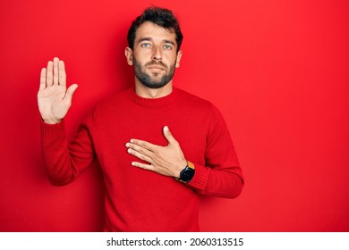 Handsome man with beard wearing casual red sweater swearing with hand on chest and open palm, making a loyalty promise oath 
