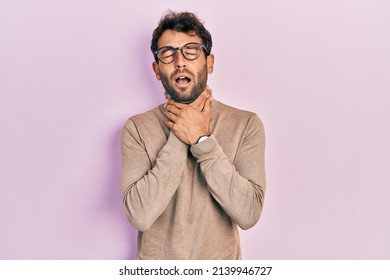 Handsome man with beard wearing turtleneck sweater and glasses shouting and suffocate because painful strangle. health problem. asphyxiate and suicide concept. 