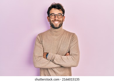 Handsome man with beard wearing turtleneck sweater and glasses happy face smiling with crossed arms looking at the camera. positive person.  - Powered by Shutterstock