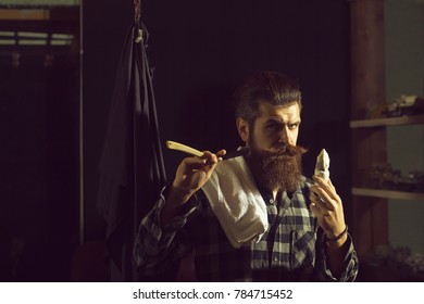 Handsome Man, Bearded Hipster, Brunette With Long Beard And Moustache Shaves With Open Vintage Razor With Blade And Shaving Brush On Dark Background