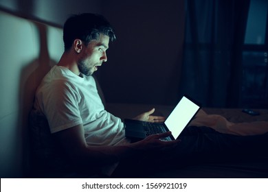 Handsome Man In Bed And Laptop Open Dark Room