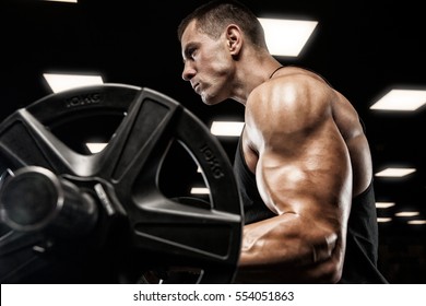 Handsome man with big muscles, posing at the camera in the gym