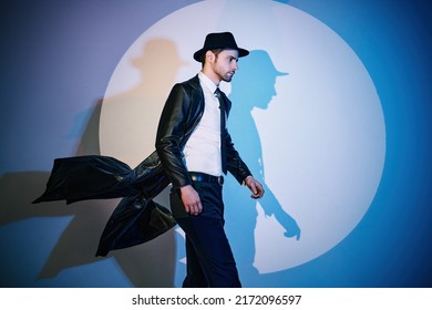 Handsome Man In Black Coat And Hat Walking Like Superhero In The Spotlight With Copy Space. Noir Film Style. Private Detective, Spy, Investigation Concept