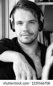 Handsome Man With Black Shirt Sitting In Bay Window Seat Listening To Music On Headphones