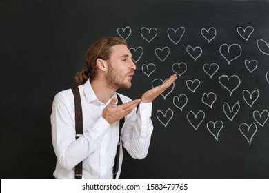 Handsome man blowing kiss dark background  Valentine's Day celebration