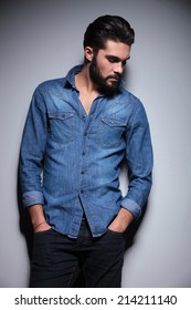 Handsome man in blue shirt posing againt the wall with his hands in pocket