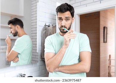 Handsome man brushing teeth in the bathroom. Morning routine and self care concept