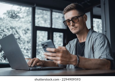 Handsome man call in smartphone, happy face, outdoor hipster portrait on the cafe, smile happy face, listen music on headphones, text, messenger, hipster, player,photo concept, laptop, coffee cup