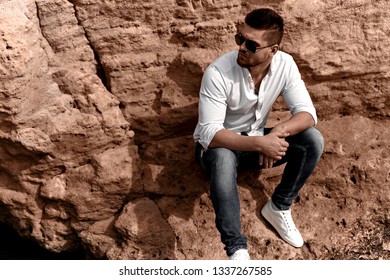 handsome man, in casual style, sitting on a stone. life style