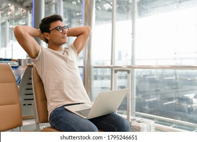 A Handsome Man In A Casual Style Is Worry Free Expression Looking Far To The Copy Space, Optimistic Man Put Laptop Over His Leg While Open His Arm To Relax From Stress Work. Work Anywhere Concept.