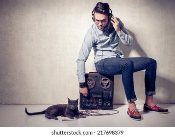 handsome man and cat listening to music on a magnetophone against grunge wall