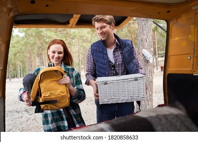 Handsome man and charming woman unload picnic items from the car with inspiration. Camping concept - Powered by Shutterstock