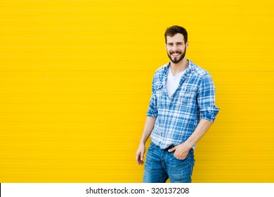 Handsome Man In Checkered Shirt Smiling On Yellow Background