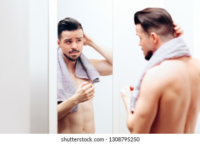 Handsome Man Checking Himself in the Mirror. Attractive guy getting ready following beauty care routine
