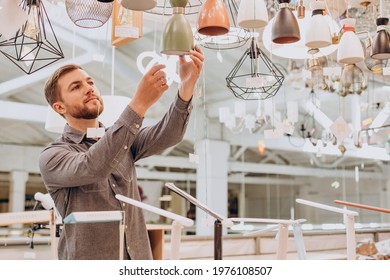 Handsome man choosing chandelier in a building market