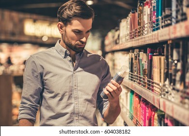 Handsome Man Is Choosing Cosmetics While Doing Shopping At The Supermarket