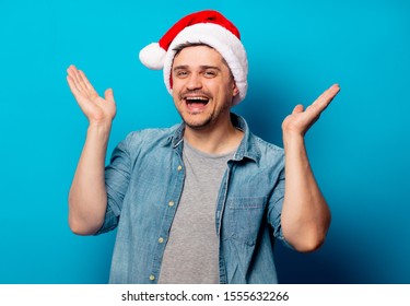 Handsome man in Christmas hat on blue background  - Shutterstock ID 1555632266