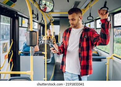 Handsome man commuting to work by bus while using a smartphone. Bearded hipster guy in checkered shirt is reading emails on a display of a smartphone during his ride. People travel transport concept. - Powered by Shutterstock