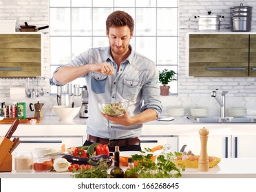 Handsome man cooking at home preparing salad in kitchen. - Powered by Shutterstock
