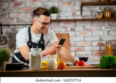 Handsome Man Cooking In The Kitchen And Talking On His Mobile Phone.