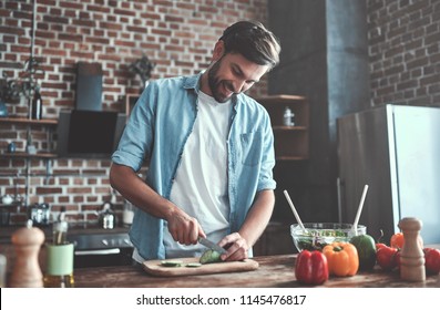 Handsome Man Is Cooking On Kitchen And Smiling.